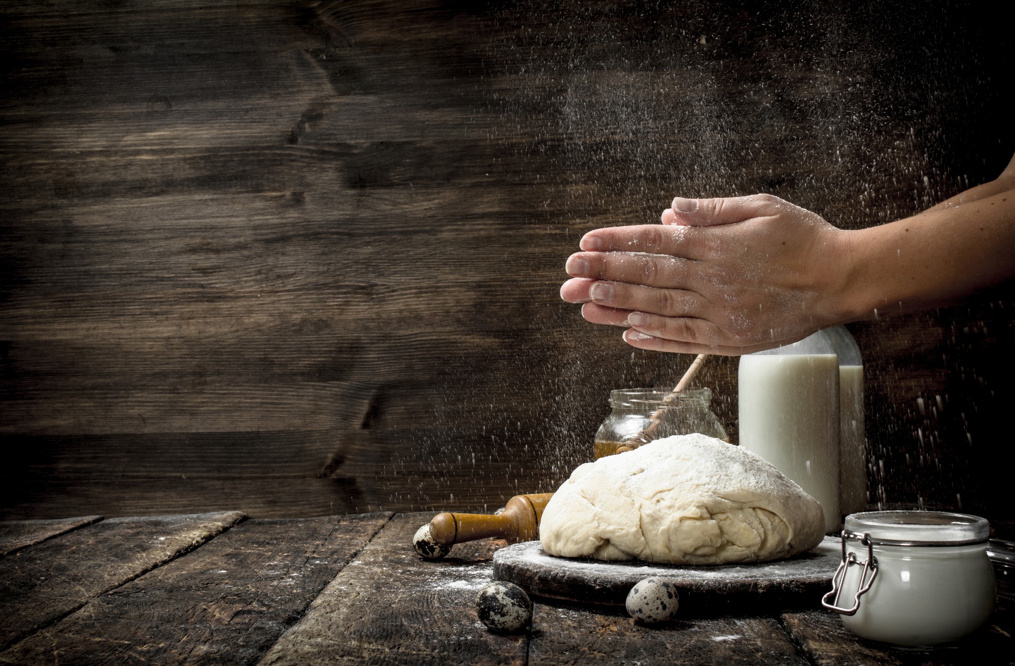 Hands kneading dough on wooden table